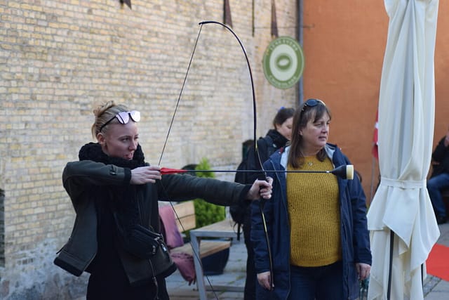 I en lille gård langs Rådhusgad i Stege, ligger en lille cafe og Lene Evers chokolade. I anledning af Æbledagen, havde nogen sat en manekin op med et æble på hoved. I den anden ende af gården lå bue og pil. Vi tog udfordringen op.